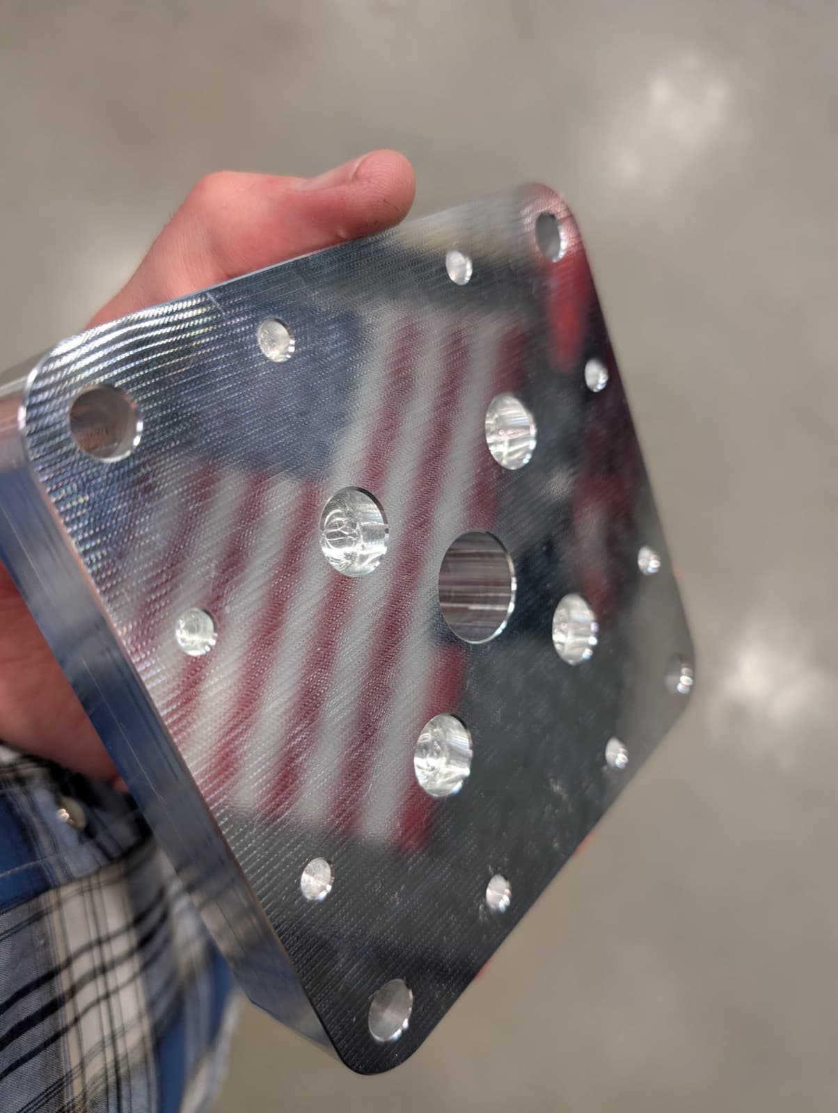 A precision-machined aluminum mold base plate held in hand