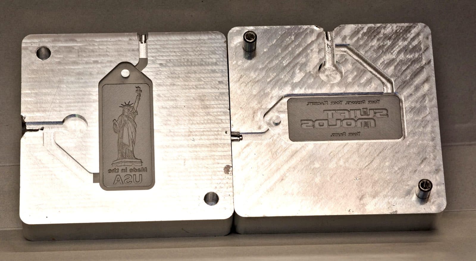 Two halves of a machined aluminum SwiftMolds mold, showing the part cavity and runner